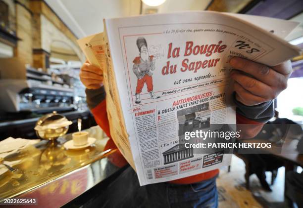 Une personne lit dans un café, le 29 février 2008 à Paris, "La Bougie du Sapeur", le quotidien humoristique lancé en 1980 qui ne sort en kiosque que...
