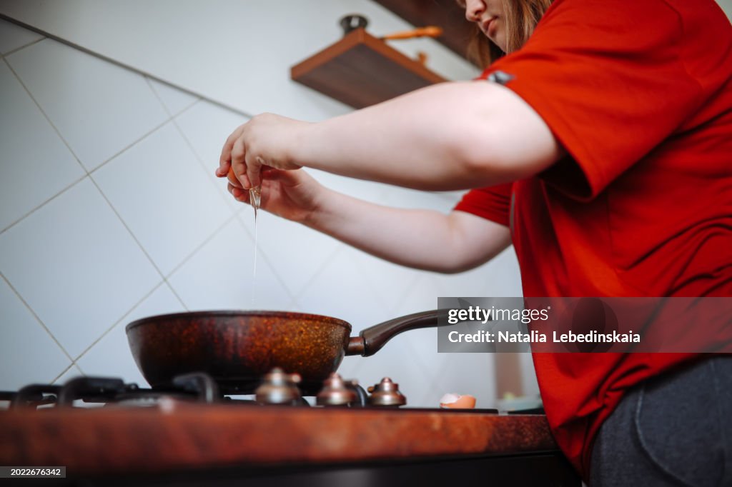 Culinary Independence: Overweight Teen Girl Cooking a Nutrient-Rich Breakfast in the Kitchen.