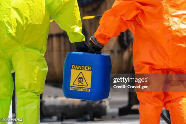 hazmat team, close up shot both of hazmat teamwork hold the hazard chemical tank to collect the danger material from site to safety storage area. - beschermend pak stockfoto's en -beelden