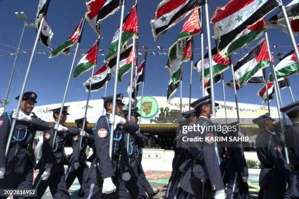 Iraqi airforce cadets hold up Iraqi and Palestinian flags during a military parade 28 April 2001 in Takrit, north of Baghdad, as they celebrate Iraqi...