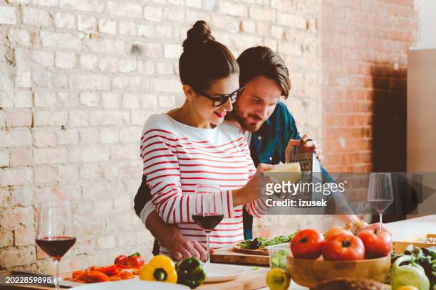 couple cooking in the modern kitchen, preparing pizza - italian food and wine stock pictures, royalty-free photos & images