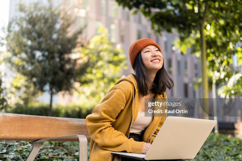 Asian female using laptop outside university in campus