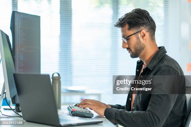 software developers using computer to write code sitting at desk with multiple screens work remotely in home at daytime. programmer and coding development concept. - web programmer stock pictures, royalty-free photos & images