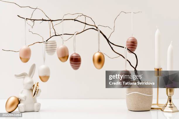 pastel golden easter eggs on branches and ceramic easter bunny - bunny eggs stock-fotos und bilder