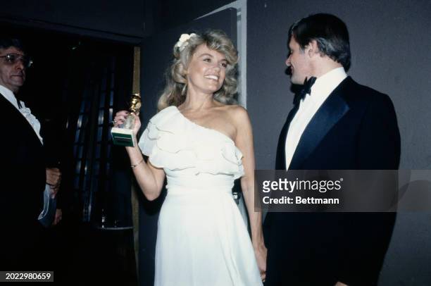 Dyan Cannon, with British actor Anthony Hopkins, after being named best supporting actress for her performance in 'Heaven Can Wait' at the 36th...