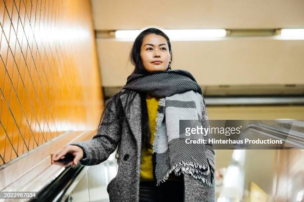 woman wearing warm clothes rides escalator - long coat stock pictures, royalty-free photos & images