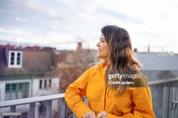 woman leaning at balustrade on balcony - balustrade stock pictures, royalty-free photos & images