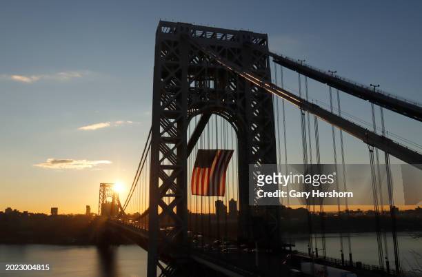 Vehicles cross the George Washington Bridge linking New Jersey to New York City as it displays its 60 by 90-foot American flag at sunrise to mark...