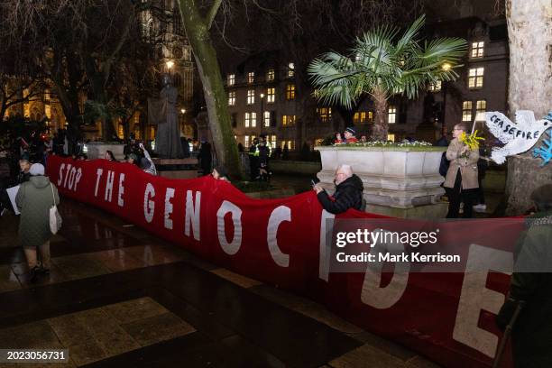 Pro-Palestinian activists stand behind a large banner reading 'Stop The Genocide' during a protest outside Parliament on the occasion of a debate and...
