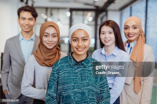 successful group of business people in modern office, looking at camera and smiling. south-east asian and chinese business people. focus on young businesswoman - malaysia culture stock pictures, royalty-free photos & images