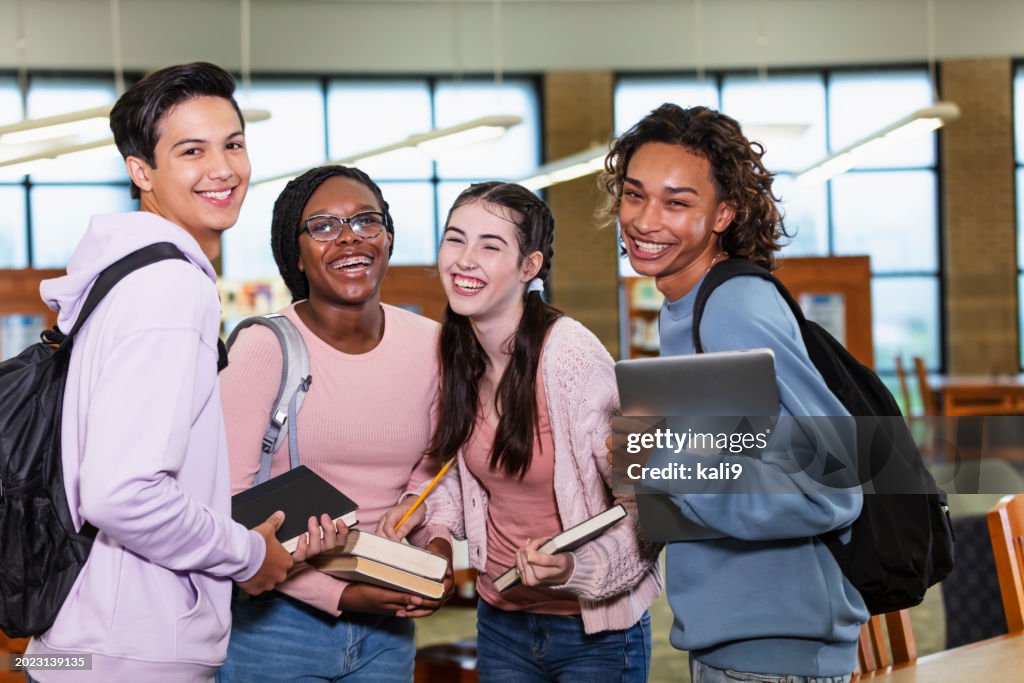 Vier multiethnische Gymnasiasten in einer Bibliothek