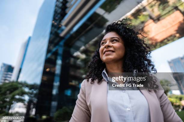 reife geschäftsfrau, die wegschaut und über die natur nachdenkt - business woman stock-fotos und bilder