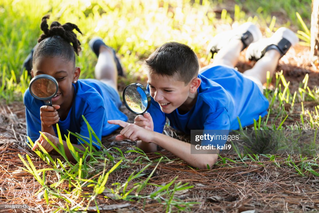Two children with magnifying glasses explore environment