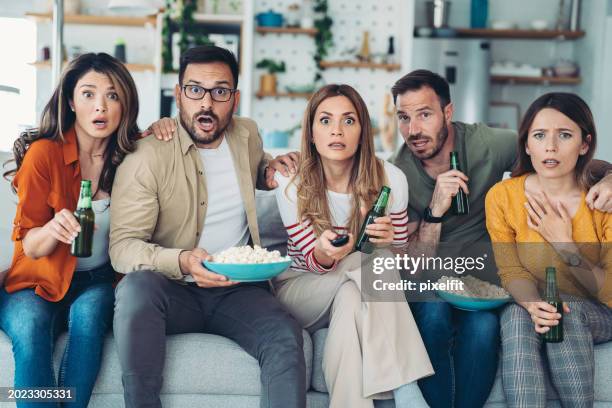 group of friends with shocked expressions watching tv together - group video conference stock pictures, royalty-free photos & images