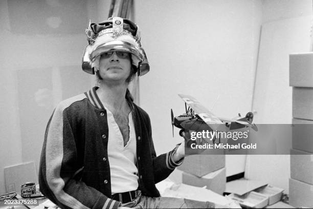 Doug Kenney, National Lampoon magazine founder, with a crown on his head and a model plane in his hand in National Lampoon headquarters, New York...