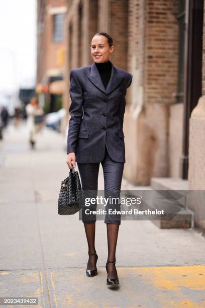 Guest wears a black turtleneck pullover, a gray oversized blazer jacket , a skirt, a black woven leather bag, tights, black pointed shoes, outside...