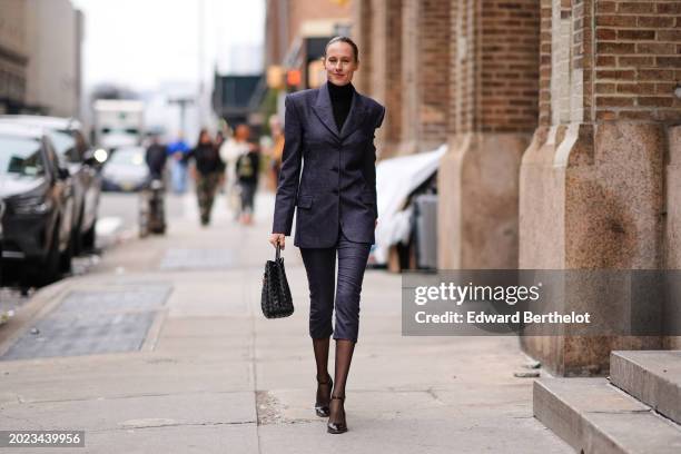 Guest wears a black turtleneck pullover, a gray oversized blazer jacket , a skirt, a black woven leather bag, tights, black pointed shoes, outside...
