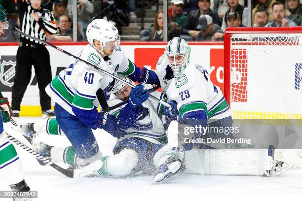 Elias Pettersson and Filip Hronek collide with Casey DeSmith of the Vancouver Canucks against the Minnesota Wild in the second period at Xcel Energy...