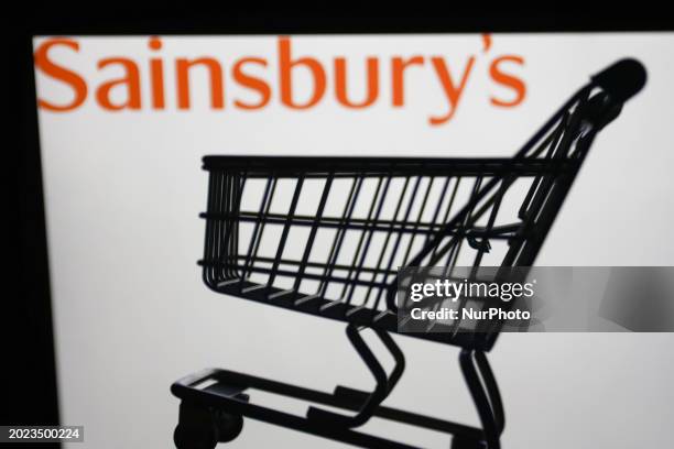 Sainsbury's logo displayed on a laptop screen and a small shopping cart are seen in this illustration photo taken in Krakow, Poland on February 22,...