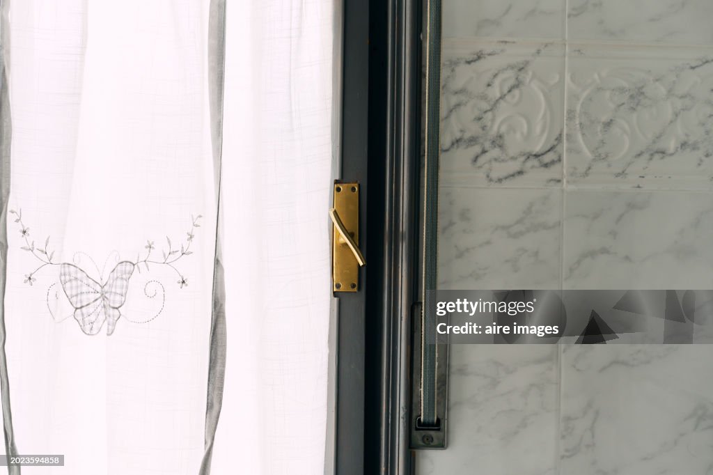 Front view of a glass window with curtains in the interior of a house next to a window