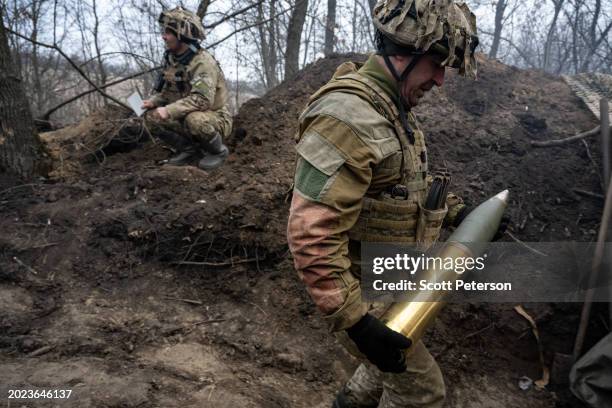 Ukrainian soldier who gave the name Ruslan carries a shell to load the gun, as soldiers of the Ukraine Armys 95th Brigade fire 105mm artillery shells...