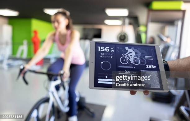 mujer en forma haciendo una prueba de esfuerzo mientras monta en bicicleta en un gimnasio - técnica de imágenes fotografías e imágenes de stock