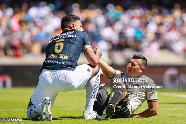 Nathanael Ananias of Pumas helps Daniel Álvarez of Puebla during the 6th round match between Pumas UNAM and Puebla as part of the Torneo Clausura...