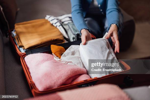 persona che imballa i vestiti in una valigia arancione per un viaggio - imballare foto e immagini stock