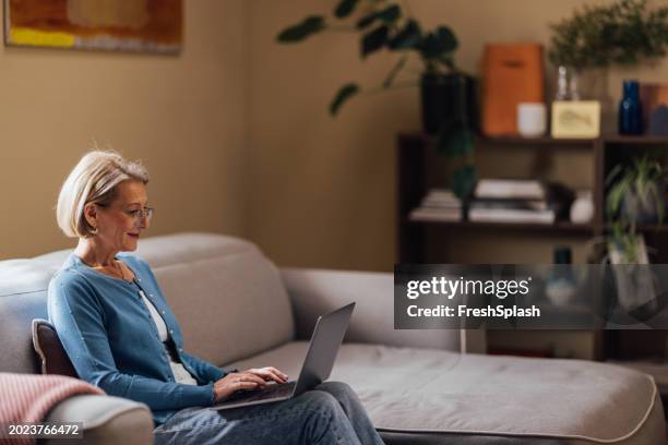 senior woman enjoying her time working on laptop at home - financial literacy stock pictures, royalty-free photos & images