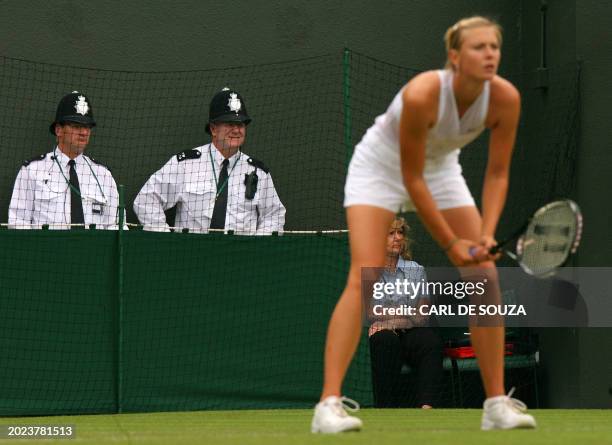 Two British policemen watch as Maria Sharapova of Russia plays against Stephanie Foretz of France in the opening round on day two of the 2008...