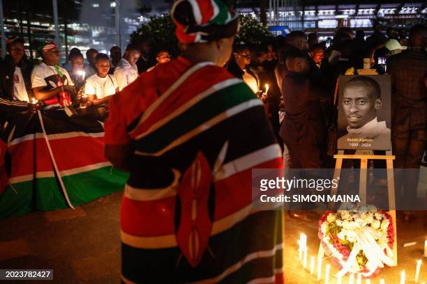 Woman wrapped with the national flag of Kenya pays her respect in front of a photo of late Kenyan marathon runner Kelvin Kiptum during a candle light...