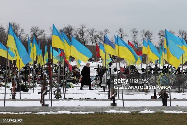 An elderly woman walks among the graves along the Alley of Heroes where Ukrainian soldiers who died in the Russian-Ukrainian war are buried, in...