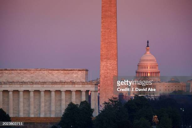 The setting sun glistens off of the US Capitol Dome, right, as the sky turns pink behind the Lincoln Memorial, left, and the Washington Monument,...