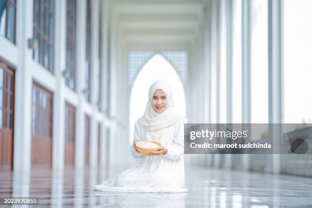 zakat, muslim hands are holding a wooden bowl of rice grains for zakat, an islamic zakat concept - seed saving stock pictures, royalty-free photos & images