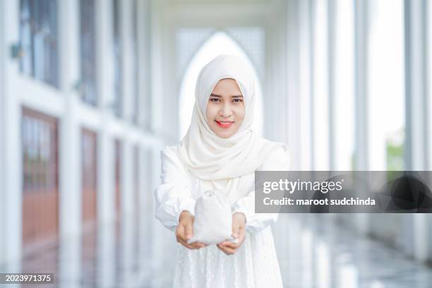 zakat, muslim hands are holding a wooden bowl of rice grains for zakat, an islamic zakat concept - seed saving stock pictures, royalty-free photos & images