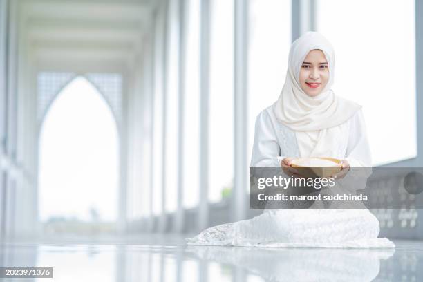 zakat, muslim hands are holding a wooden bowl of rice grains for zakat, an islamic zakat concept - seed saving stock pictures, royalty-free photos & images