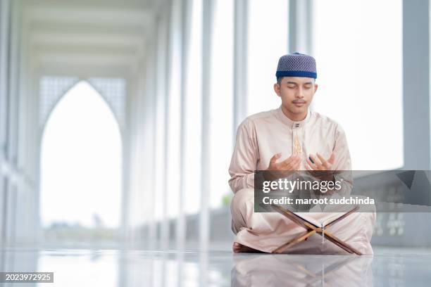 ramadan, an asian muslim man is sitting and reading the quran. the peace in the mosque - friday stock pictures, royalty-free photos & images