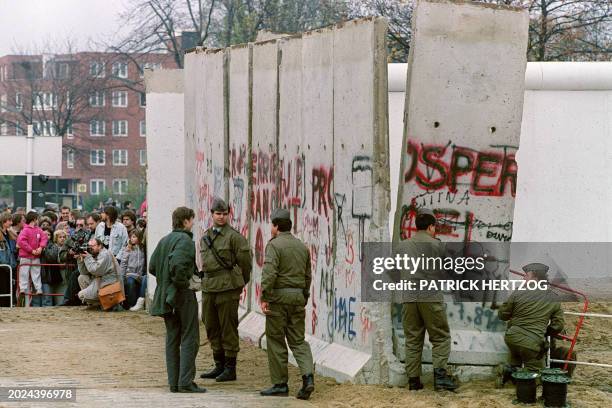 East German border guards continue to work as they demolish a section of the Berlin Wall, between East berlin and the no-man's-land, to open a new...