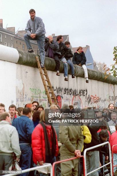 East Berliners stand on top of the Berlin Wall, on November 11 at a section of the Berlin Wall, between East berlin and the no-man's-land, destroyed...