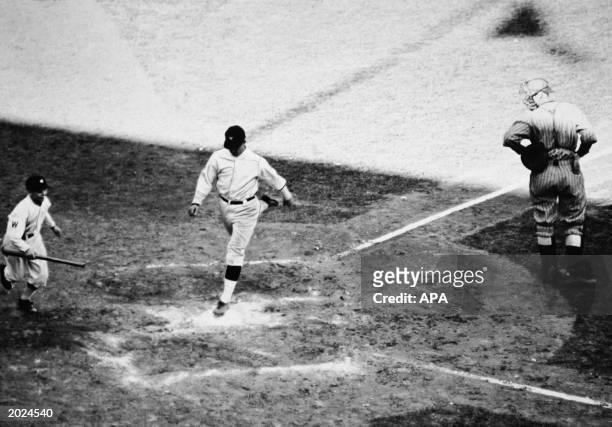 American baseball player Stanley "Bucky" Harris , playing for the Washington Senators, lands on home plate after scoring a homerun during the seventh...