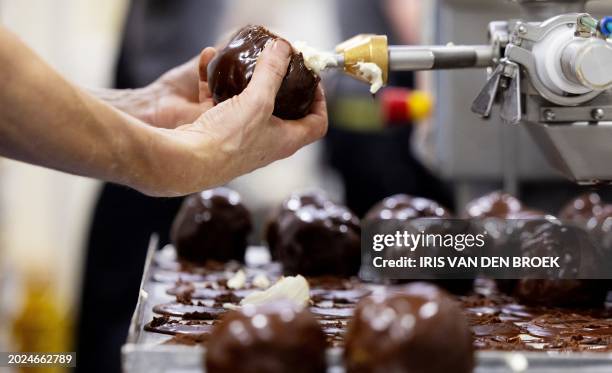 Worker prepares Bossche bollen also known as 'chocolate ball', a pastry specialty baked from choux batter, dipped in melted dark chocolate and filled...