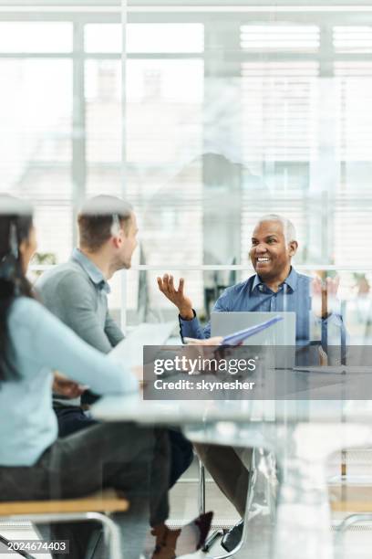 latin senior agent talking to a couple on a meeting in the office. - vertical stock pictures, royalty-free photos & images