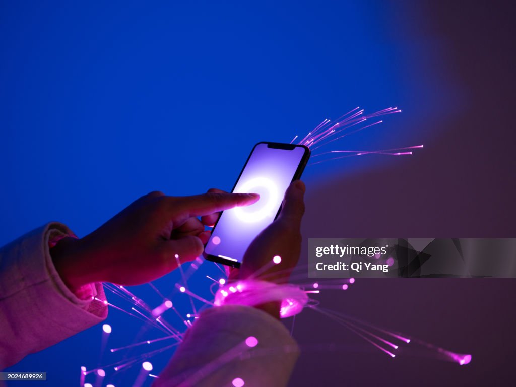 Close-up of holding smartphone, arms wrapped with fiber optics