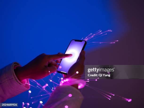 close-up of holding smartphone, arms wrapped with fiber optics - qi yang stock pictures, royalty-free photos & images