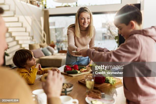 madre e hijo felices sirviendo comida a su familia en el comedor. - meal fotografías e imágenes de stock