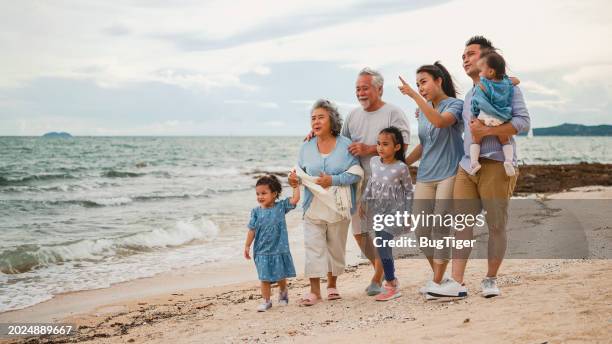 cheerful family and happy cute little daughter walk by the sea, enjoy the sea view and play together on vacation. - familie met meerdere generaties stockfoto's en -beelden