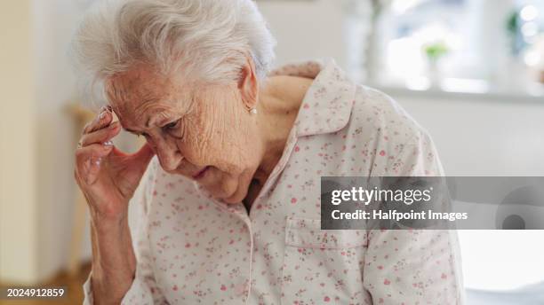 senior woman has headache, feeling dizzy after waking up. elderly woman in pyjamas sitting on bed, holding her head. - demens bildbanksfoton och bilder