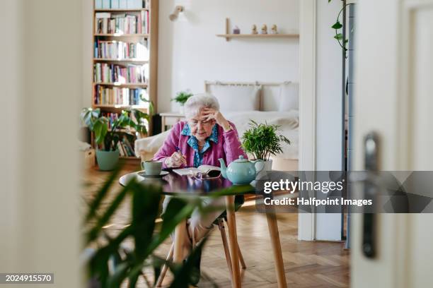 portrait of elderly woman solving sudoku puzzles at home, sitting in living room. sudoku as popular game for aging people, logical thinking, problem solving. - brain games seniors stock pictures, royalty-free photos & images