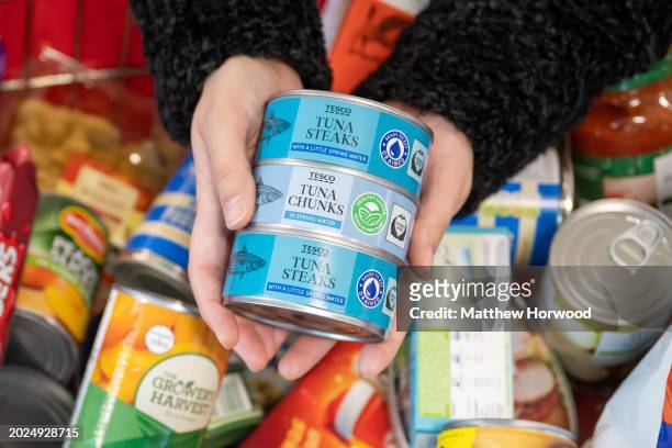 In this photo illustration, A person holds a tin of tuna steaks at a food bank on November 20, 2021 in Cardiff, Wales.