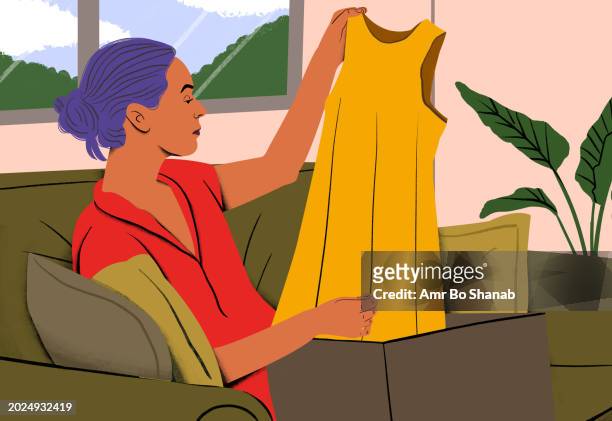 woman admiring a new yellow dress at home, experiencing a joyful unboxing moment. online shopping, fashion, home lifestyle, joy of life, new purchase, self-treat, unwrapping - new content stock pictures, royalty-free photos & images